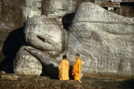 MONKS IN FRONT OF LYING BUDDHA STATUE, POLONNARUWA, SRI LANKA