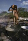 INDIAN WOMAN NUDE BOILING MANIOK PULP IN A NATIVE PATTERY AT THE VILLAGE SQUARE, XINGU INDIAN RESERVATION, BRAZIL