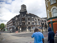 Aftermath of the Tottenham riots . local residents survey the damage including  a burnt out police van and Carpet Right Building gutted by arson . the building dates back to the 1930's . local MP David Lammy is also pictured visiting the scene with local 