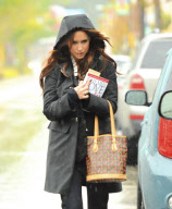 A Somber Looking Jennifer Love Hewitt Heads Out In The Rain Carrying The Book "Why Men Love Bitches"