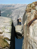 Hikers stand on Kjeragbolten boulder wedged 1,000m up between two cliff faces, Kjerag Mountains, Norway - 2003