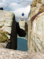 Hikers stand on Kjeragbolten boulder wedged 1,000m up between two cliff faces, Kjerag Mountains, Norway - 2003