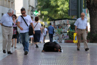 Elderly beggar woman crawling on pavement outside the Bank of Greece, Athens, Greece - 13 Jun 2012