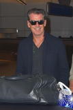 Pierce Brosnan flashes his pearly whites as he arrives at LAX with a ton of luggage