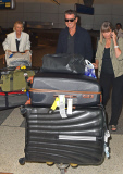 Pierce Brosnan flashes his pearly whites as he arrives at LAX with a ton of luggage