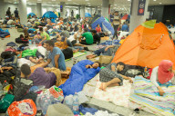 NEWS:  Flüchtlinge warten auf ein Ende der Polizeiabsperrung am Bahnhof in Budapest