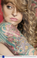 Beautiful young woman looking sideways with tattooed arm