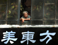 An elderly Chinese woman looks out her window in Beijing