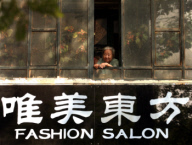 An elderly Chinese woman looks out her window in Beijing