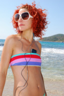 A good looking young woman, with red hair, listening to music on her mobile phon