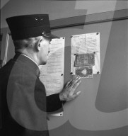 Beamter liest Bekanntmachung über gefälschte Banknoten im Umlauf; 1943