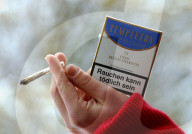 Hand mit Joint und Zigarettenpäckchen
