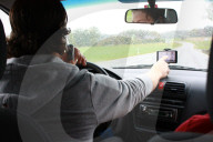 Autofahrer mit Handy und Hand am Navigationsgeraet