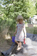 Blonde Girl playing with Hand Brush and Bucket on a Camping Ground