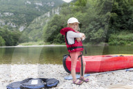 Blonde Girl standing in front of a Canoe at Riverside