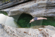 A swimmer takes a dive into the rocky creek
