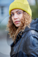 Portrait of a Woman with curly Hair wearing a yellow Beanie