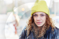 Portrait of a Woman with curly Hair wearing a yellow Beanie