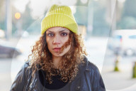 Portrait of a Woman with curly Hair wearing a yellow Beanie