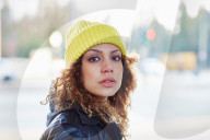 Portrait of a Woman with curly Hair wearing a yellow Beanie