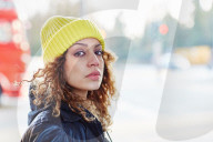 Portrait of a Woman with curly Hair wearing a yellow Beanie