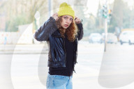 Portrait of a Woman with curly Hair wearing a yellow Beanie