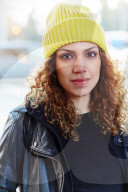 Portrait of a Woman with curly Hair wearing a yellow Beanie