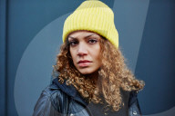 Portrait of a Woman with curly Hair wearing a yellow Beanie