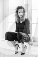 Portrait of a Woman with curly Hair sitting on a Window Sill
