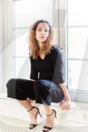 Portrait of a Woman with curly Hair sitting on a Window Sill