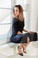 Portrait of a Woman with curly Hair sitting on a Window Sill