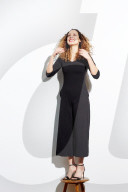 Portrait of a Woman with curly Hair balancing on a Stool
