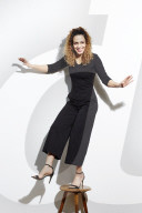 Portrait of a Woman with curly Hair balancing on a Stool