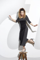 Portrait of a Woman with curly Hair balancing on a Stool