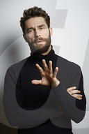 Portrait of a Man wearing a black Turtleneck and discussing a Topic