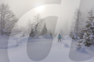 Woman spurts through fresh snow through winter landscape