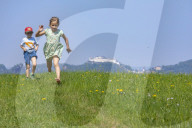 Girl and Boy running up and down a Meadow nearby Salzburg
