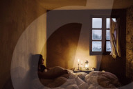 Wabi-Sabi Living Concept, Bedroom, Woman lying in Bed and looking out of the Window