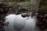 Woman refreshes herself at a Creek