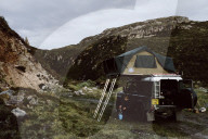 Woman preparing a Meal with a Camp Cooker outdoors on a Road Trip