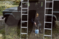 Woman preparing a Meal with a Camp Cooker outdoors on a Road Trip