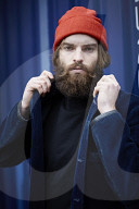 Man with red Beanie posing in front of a blue Container 
