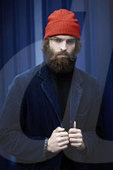 Man with red Beanie posing in front of a blue Container 