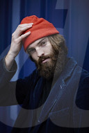 Man with red Beanie posing in front of a blue Container 