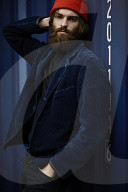 Man with red Beanie posing in front of a blue Container 