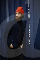 Man with red Beanie posing in front of a blue Container 