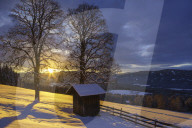 A bee hut beside a mountain farm at sunrise
