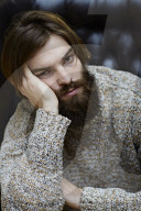 Young Man wearing a wool Pullover and sitting on an Armchair