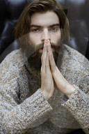 Young Man wearing a wool Pullover and sitting on an Armchair