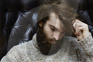 Sad young Man wearing a wool Pullover and sitting on an Armchair